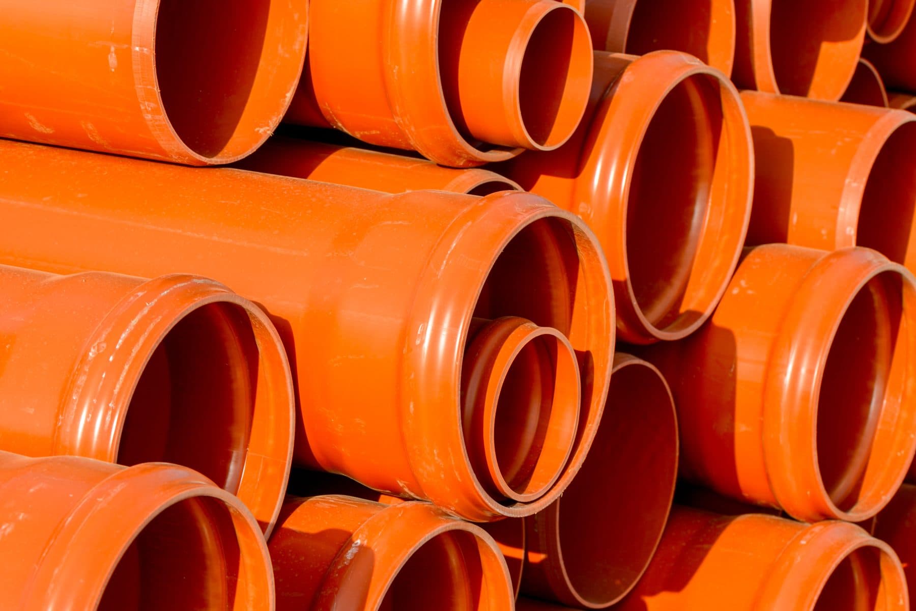Stablede orange PVC-kloakrør klar til kloakarbejde
