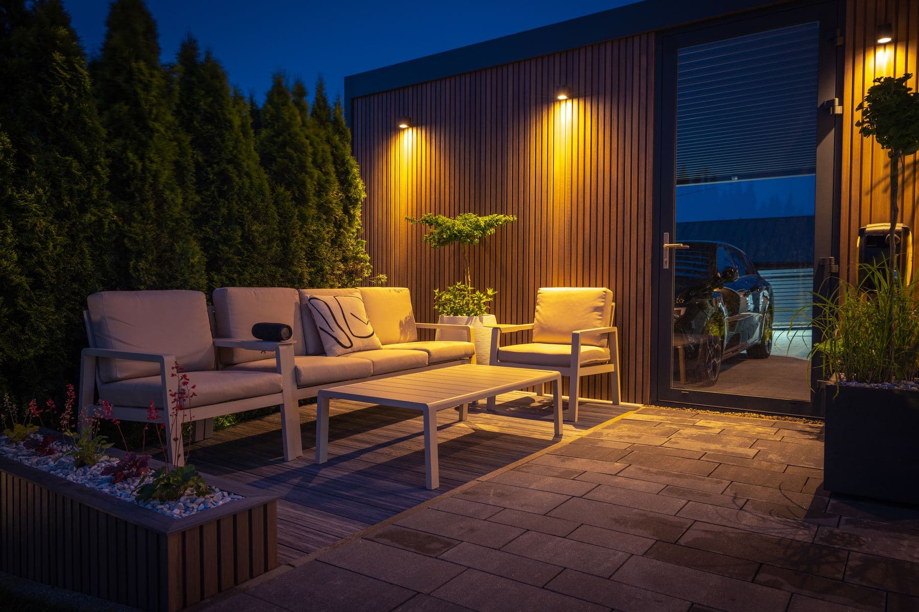 Lodret træbeklædning og terrasse med loungemøbler i aftenbelysning